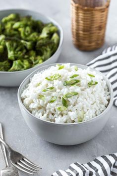 two bowls filled with rice and broccoli on top of a table next to silverware