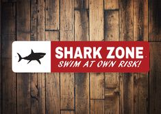 a sticker that says shark zone swim at own risk on the side of a wooden wall