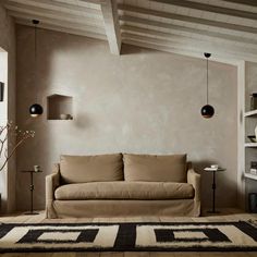 a living room with a couch, rug and shelves on the wall in front of it