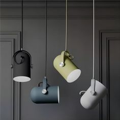 three different colored lamps hanging from the ceiling in a room with gray walls and black doors