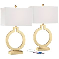 two lamps with white shades on them and one has a phone plugged into it