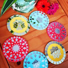 colorful paper plates sitting on top of a wooden table next to a vase with flowers