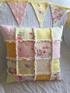 a pillow made out of patchwork and fabric with flowers on the front, sitting on a bed