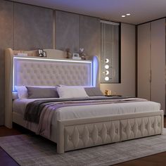 a bedroom with a large bed and lights on the headboard, along with an area rug