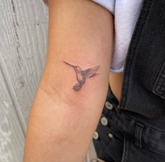 a small hummingbird tattoo on the arm