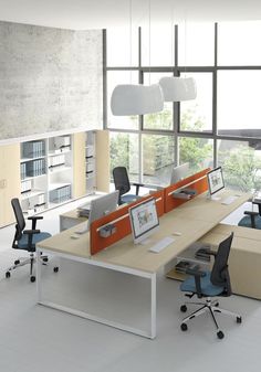 an office with desks and chairs in front of large windows