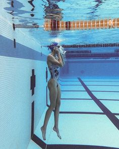 a woman in a swimming suit is standing under the water and talking on her cell phone