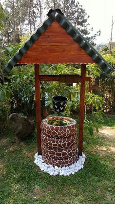 a small wooden structure with rocks and plants in the center, on top of grass