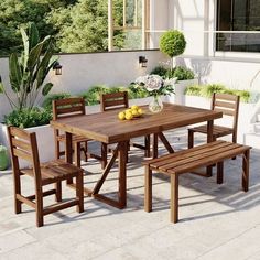 a wooden table with four chairs and two benches in front of a white house on a sunny day