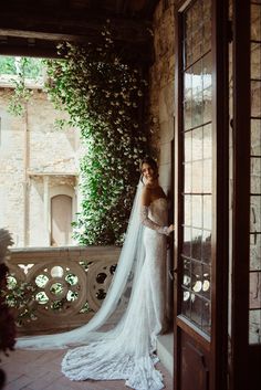 a woman in a wedding dress standing on a balcony with her veil over her head