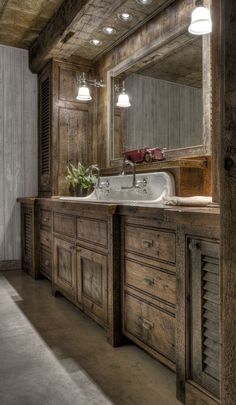 a bathroom with wooden cabinets and a large mirror on the wall over the sink is lit by two lights