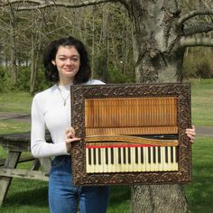 a woman holding up an old piano in front of a tree