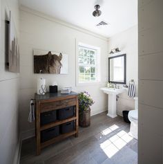 a bathroom with white walls and wood flooring