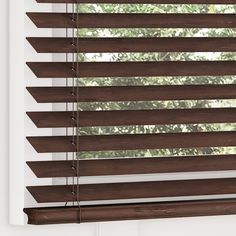 a window with wooden blinds in front of trees