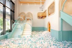 an indoor play area with blue and white balls on the floor, slides in between two walls