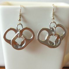 pair of silver heart shaped earrings sitting on top of a white cup