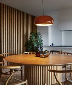 a round wooden table surrounded by chairs and a potted plant on top of it