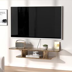 a flat screen tv mounted to the side of a wall next to a wooden shelf