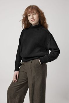 a woman in black sweater and pants posing for the camera with her hands on her hips