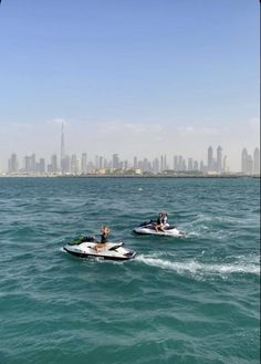 two people on jet skis in the ocean with city skyline in the backgroud