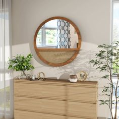 a wooden dresser topped with a mirror and potted plant next to a window in a living room