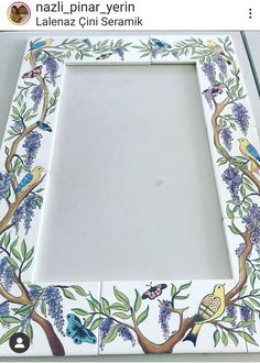 a white frame with blue flowers and birds painted on the sides, sitting on a table