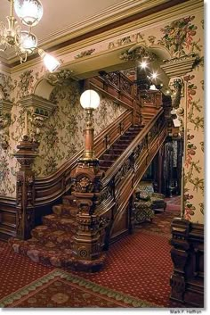 an ornate staircase in a house with floral wallpaper on the walls and carpeted floor