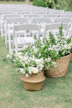 two baskets filled with white flowers sitting on top of a grass covered field next to rows of chairs