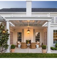 an outdoor patio with wicker chairs and potted plants on the front porch area