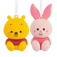 two cartoon shaped items hanging from strings on a white background, one is pink and the other is yellow