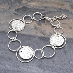 This stylish 950 silver link bracelet is presented by Pakaon Sojintarit who works with artisans of the Karen hill tribe in Thailand. Hammered discs join forces with polished round links in assorted sizes. The result is a fun contemporary accessory to wear anywhere. Modern Sterling Silver Round Chain Bracelet, Modern Round Sterling Silver Bracelets, Modern Round Sterling Silver Bracelet, Modern Silver Round Chain Bracelet, Adjustable Round Chain Bracelet With Polished Finish, Modern Silver Round Disc Jewelry, Modern Handmade Round Sterling Silver Bracelet, Bohemian Sterling Silver Round Bracelet, Modern Hammered Round Bracelets