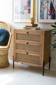 a wicker chair sitting next to a wooden cabinet with a blue cushion on it