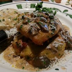 a white plate topped with meat covered in gravy and cheese next to an eggplant