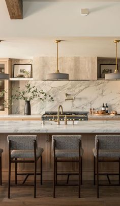 a kitchen with marble counter tops and wooden chairs in front of an island that has four stools on it