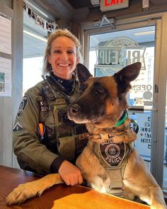 a woman in an air force uniform sitting at a table with a dog on her lap