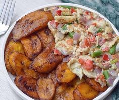 a white plate topped with potato wedges and guacamole salad next to a fork