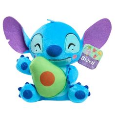 a blue stuffed animal with an avocado on it's chest and purple ears