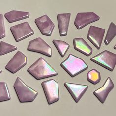 several different shapes and sizes of purple opal stones on a white surface with light reflection