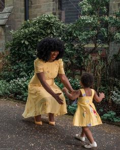 a woman in yellow dress holding hands with a small child