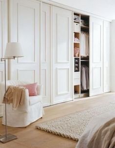 a bedroom with white closets and carpeted flooring