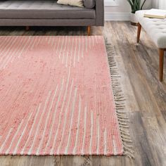 a living room with a gray couch and pink rug