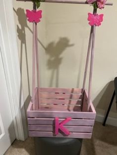 a wooden swing with pink flowers on it and the letter k painted on the bottom