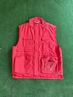 "Vintage 80s red Nylon vest Back to the Future vibes or perfect for going fishing Size XL The outside is 100% nylon and the inside is 100% polyester.  7 pockets and a place for your pen. It Closes shut with a zipper and velcro over the zipper.  Nice and thick with adjustable velcro on the back to adjust the vest size if needed.  The vest is vintage but has never been worn before. Measurements laying flat Armpit to armpit 25\" (50\" total)  Total length of vest 27\"  Items are shipped out within Red Vest With Pockets, Red Sleeveless Vest With Pockets, Casual Red Vest With Pockets, Red Nylon Outerwear With Pockets, Blanche Devereaux, Twist Front Top, Silk Jumpsuit