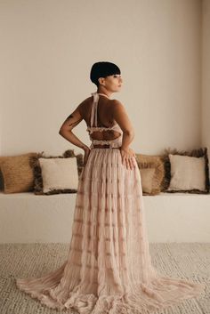 a woman standing in front of a bed wearing a dress