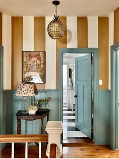 an entryway with striped walls and wooden flooring, blue doors and bench in the foreground