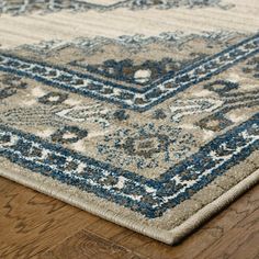 a blue and beige area rug on a wooden floor with hard wood floors in the background