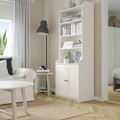 a living room with a white chair and book shelf