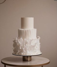 a three tiered white wedding cake sitting on top of a table