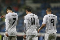 three soccer players in white uniforms standing next to each other