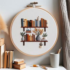 a cross stitch book shelf with books and vases